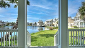 A view from a porch overlooking a lake with houses in the background.