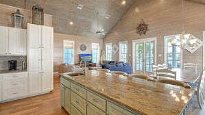A spacious kitchen with a large island, wooden ceiling, and a dining area with a chandelier.