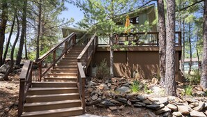 A wooden staircase leading to a cabin surrounded by trees.