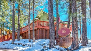 A wooden cabin with a red railing and a sign indicating 'CASITA BONITA 55 WINNING TRAIL'.