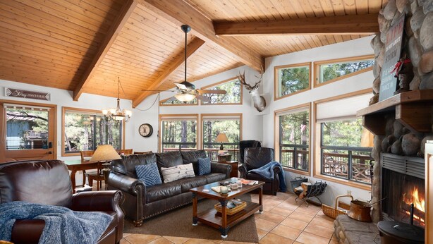 A cozy living room with a fireplace, leather furniture, and large windows.