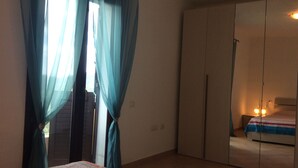 A room with a bed, a wardrobe, and a window with curtains. - Charming apartment on the mountainside near the sea (Villaputzu)