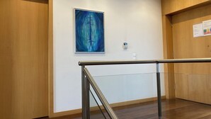 A modern hotel lobby with wooden paneling, a glass railing, and a blue abstract painting on the wall. - Luxury design villa with private heated pool, near the city of Porto! (Sanguedo)