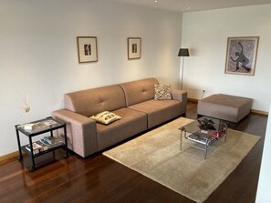 A modern living room with a sofa, ottoman, coffee table, and a floor lamp. - Luxury design villa with private heated pool, near the city of Porto! (Sanguedo)