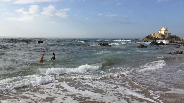 A beach with waves, a rocky outcrop, and a building on top. - Luxury design villa with private heated pool, near the city of Porto! (Sanguedo)