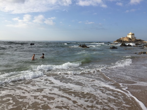 A beach with waves, a rocky outcrop, and a building on top. - Luxury design villa with private heated pool, near the city of Porto! (Sanguedo)