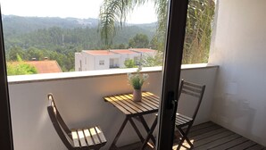 A balcony with two wooden chairs and a small table, overlooking a residential area with houses and greenery. - Luxury design villa with private heated pool, near the city of Porto! (Sanguedo)