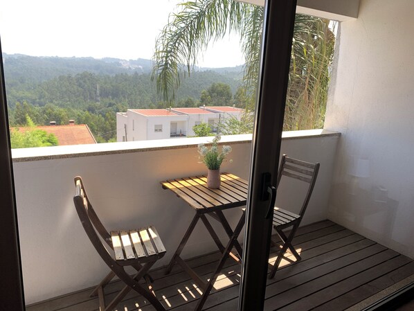 A balcony with two wooden chairs and a small table, overlooking a residential area with houses and greenery. - Luxury design villa with private heated pool, near the city of Porto! (Sanguedo)
