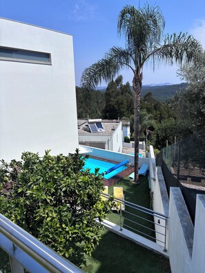 Una piscina en la azotea con tobogán, rodeada de vegetación y vistas despejadas del paisaje.