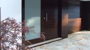 A modern building with a large glass door and a stone-tiled entrance area. - Luxury design villa with private heated pool, near the city of Porto! (Sanguedo)