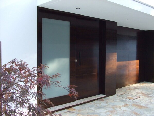 A modern building with a large glass door and a stone-tiled entrance area. - Luxury design villa with private heated pool, near the city of Porto! (Sanguedo)