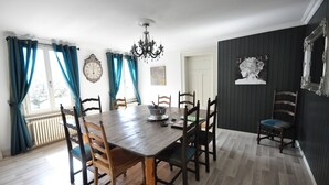 Ein Esszimmer mit Holztisch und Stühlen, einer Chandelierleuchtre und einer Uhr an der Wand.