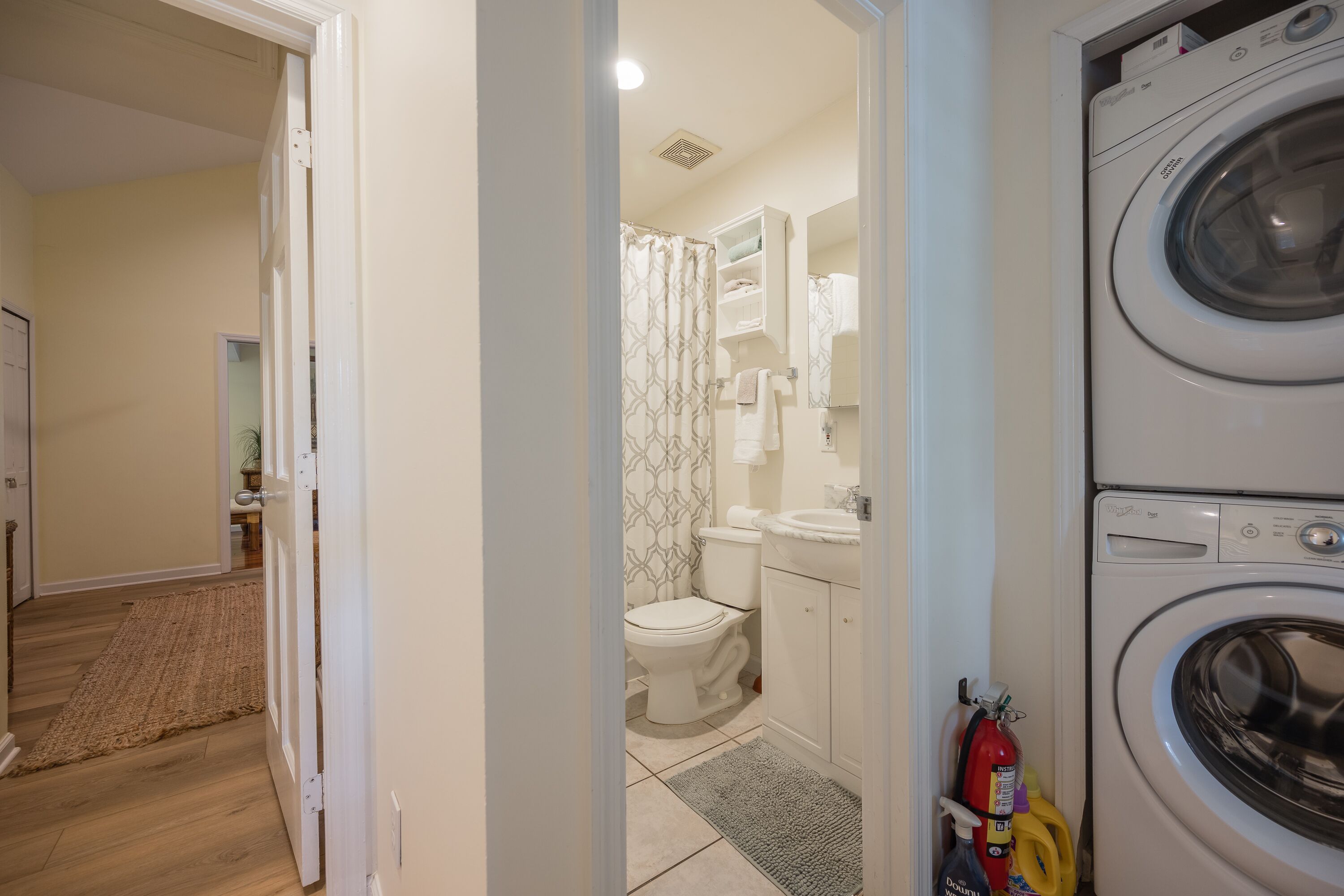 A laundry room with a washing machine, a fire extinguisher, and cleaning supplies.