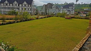 Um extenso gramado bem cuidado com um caminho que leva a uma fileira de casas tradicionais com telhados pontudos.