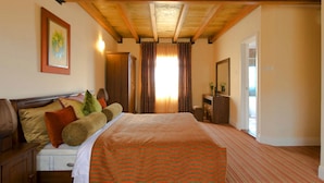 Quarto de hotel com cama, cabeceira de madeira, cômoda e espelho.