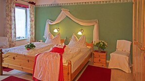 A bedroom with a wooden bed, two bedside tables, a nightstand, a window with curtains, and a small bedside table with a plant. - Farmhouse vacation rental, 55 square meters, sleeps up to 4, ideal for families (Obing)