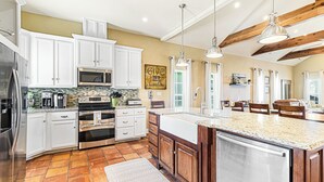 A spacious kitchen with white cabinets, a large island, stainless steel appliances, and a tiled floor. - Family-Friendly Lakeside Charmer w/ Resort-Style Amenities in Cinnamon Shore (Port Aransas)