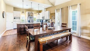 A spacious kitchen with wooden flooring, white cabinets, a central island, and pendant lighting. - Family-Friendly Lakeside Charmer w/ Resort-Style Amenities in Cinnamon Shore (Port Aransas)