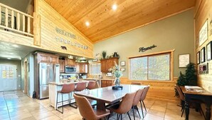 A spacious kitchen with wooden cabinets, a central island, and a dining area with chairs.