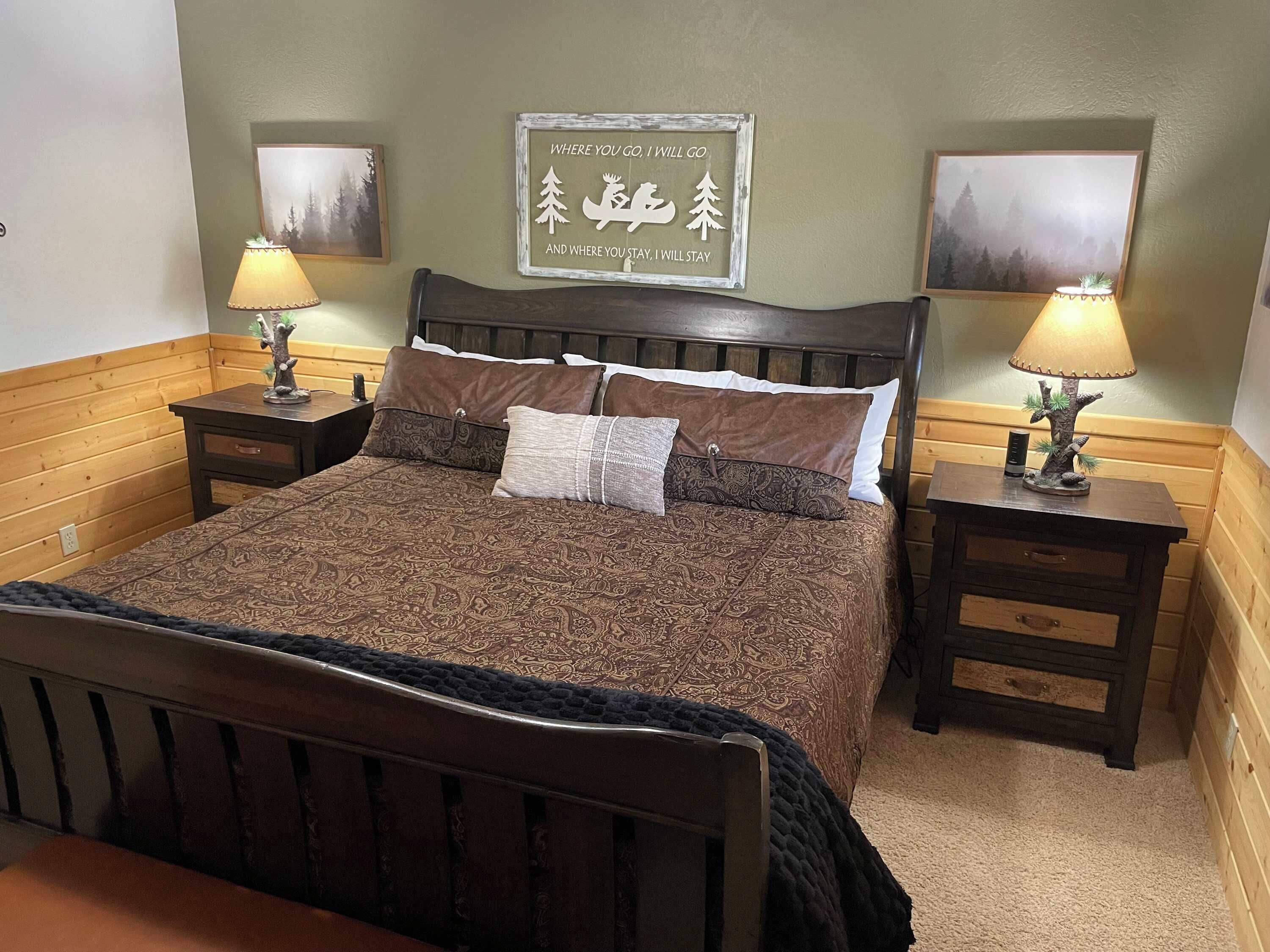 A bed with a patterned bedspread, two nightstands with lamps, and two framed pictures on the wall.