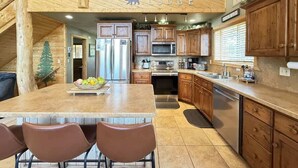 A modern kitchen with wooden cabinets, a central island, and a welcoming sign above.