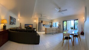 Une cuisine moderne avec un îlot central, un coin repas avec des chaises et un canapé dans le salon.
