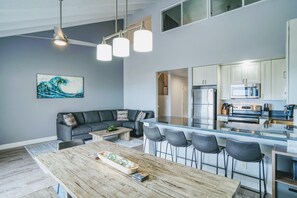 Una cucina moderna con angolo bar, un tavolo da pranzo con sedie e un divano grigio nella zona living.