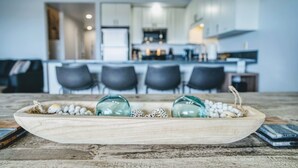 Ett träbricka med dekorativa ägg och ett glas på ett rustikt bord i ett modernt kök.
