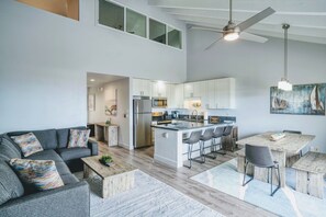 A modern kitchen with a central island, bar stools, and a dining table.