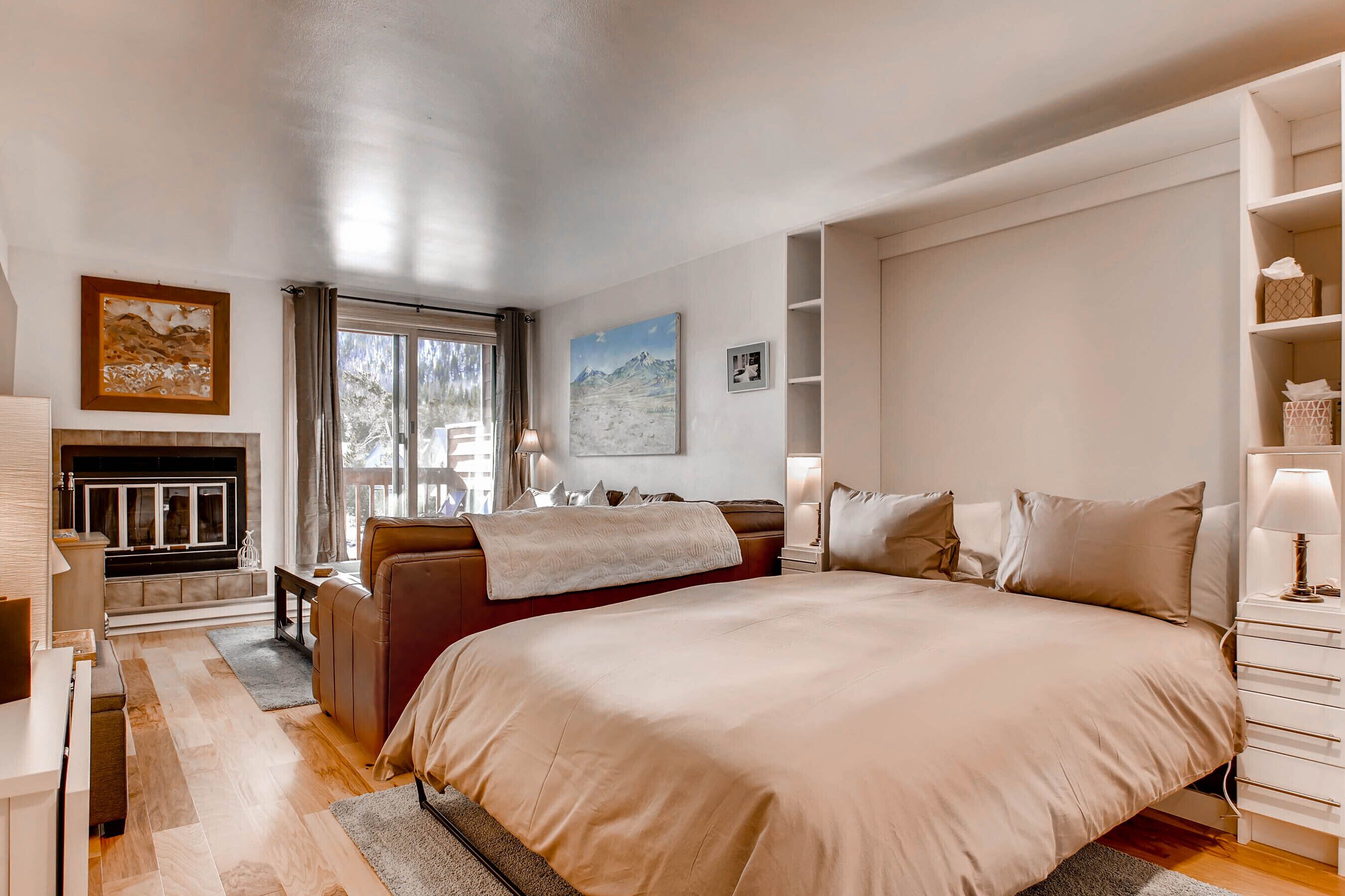 Un'ampia camera da letto con un grande letto, un divano, un camino e vista sull'esterno.