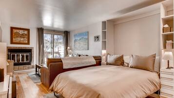 Un'ampia camera da letto con un grande letto, un divano, un camino e vista sull'esterno.
