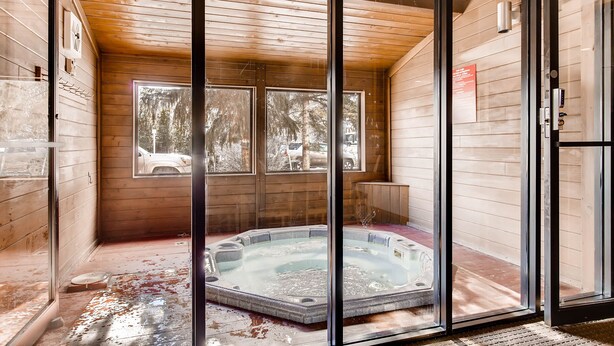 Een houten hut met een glazen deur die leidt naar een zone met een hottub.