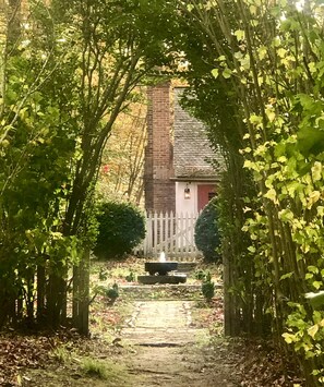 A pathway leading to a building with a brick chimney, surrounded by trees and a wooden fence. - History, Art, Nature. Built  in 1760, 110 Acres of Ancient Woodland Preserve (Surry)