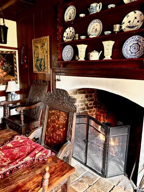 A traditional room with a fireplace, wooden furniture, and a collection of decorative plates on shelves.