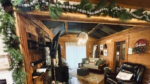 A rustic cabin interior with a wooden floor, a leather armchair, a sofa, and a fireplace. - Cedar Springs Cabin I Putting Green + Hot Tub (Hot Springs)