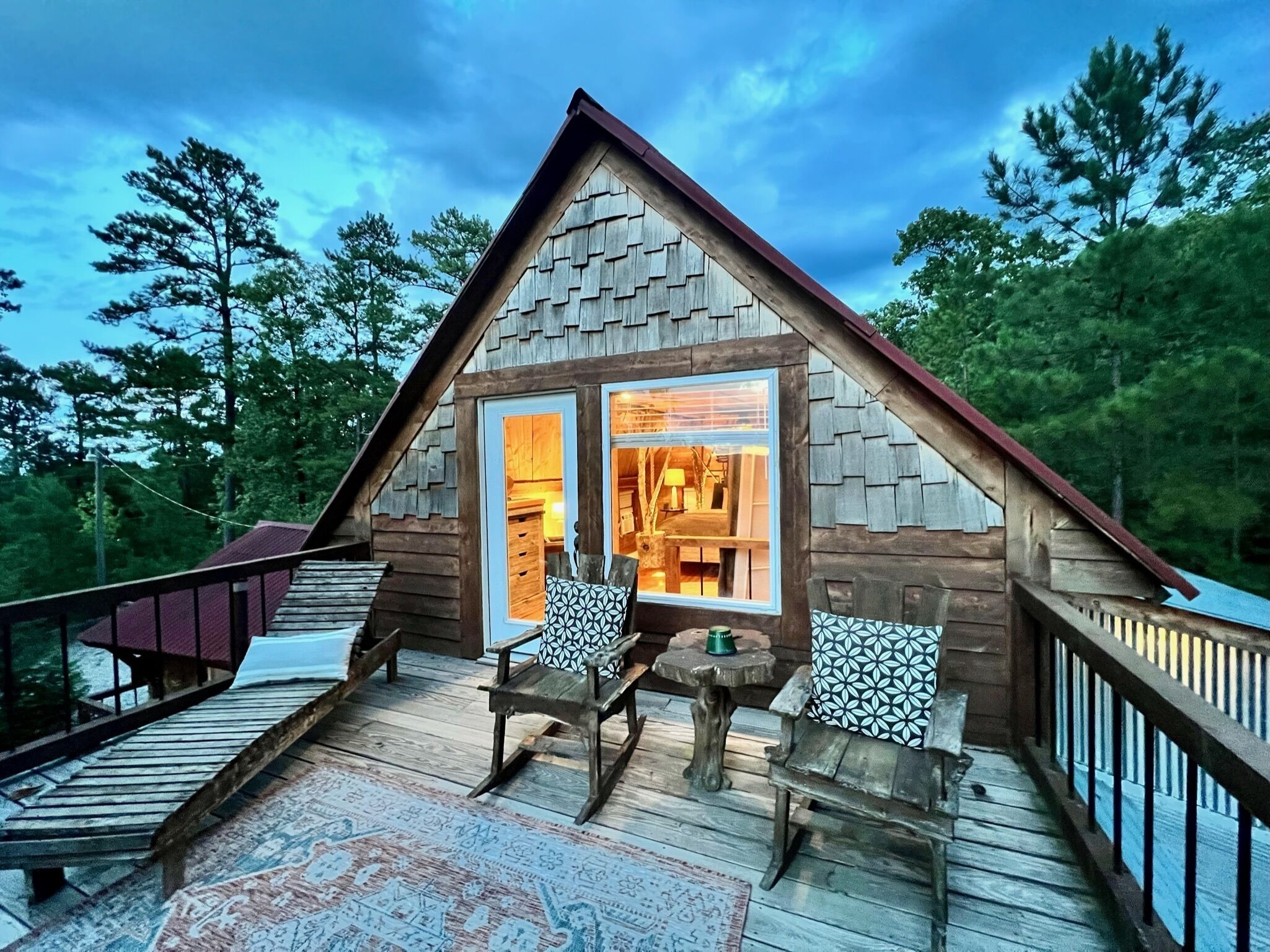 Una cabaña de madera con terraza, comedor y vistas al bosque circundante.