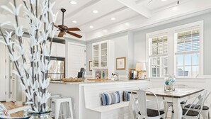 A modern kitchen with white cabinetry, a central island with seating, and a ceiling fan. - Beautiful, 3rd-Fl, Pet-Friendly Condo@Cinnamon Shore w/ Easy Amenity Access! (Port Aransas)