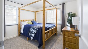 Un lit à baldaquin avec un cadre en bois, une couvre-lit à motifs bleus et blancs, et une table de chevet avec une lampe.