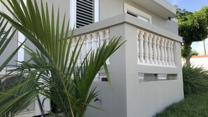 A modern building with a white exterior, a balcony with white balustrades, and a window with horizontal blinds. - Nestled on a hill with Mountain Views (Bo Cataño, Humacao)