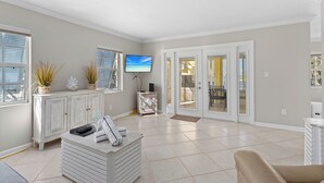 A spacious living area with a white cabinet, a television, and a sliding glass door leading to an outdoor patio.