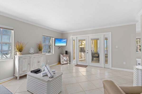 A spacious living area with a white cabinet, a television, and a sliding glass door leading to an outdoor patio.