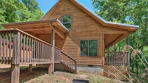 Een houten chalet met een overdekte veranda en een trap naar de ingang.