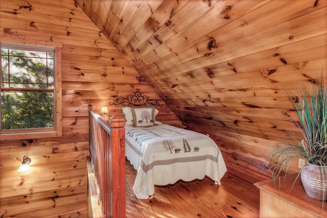 Une chambre confortable dans un chalet en bois, avec un lit, une fenêtre et une plante en pot.