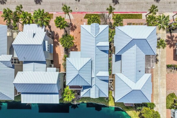 A modern hotel with geometric roof designs, a swimming pool, and palm trees.