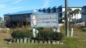 Señal del Savannah Beach & Racquet Club, con vista al edificio y la vegetación circundante.