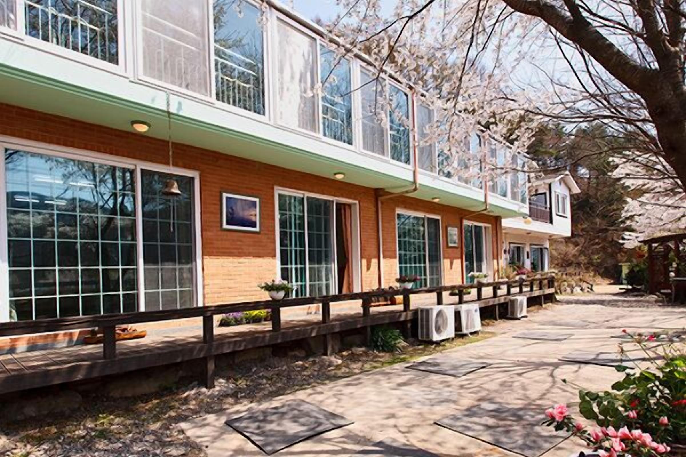 A two-story building with large windows, a brick facade, and a covered outdoor area with a wooden deck.