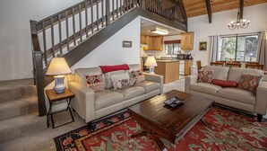 A spacious living area with two sofas, a coffee table, and a staircase leading to an upper level.