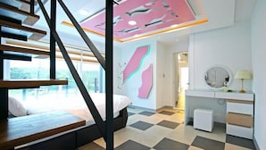 A modern bedroom with a staircase, a bed, a vanity with a mirror, and a wall with abstract art. - Gyeongju The one Pension - Blue (Gyeongju)