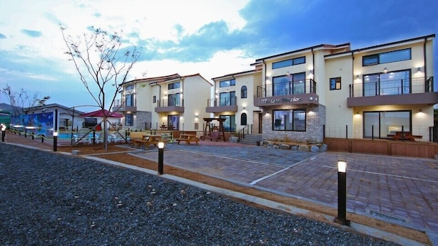 A modern hotel with multiple floors, outdoor seating, and a well-lit entrance. - Gyeongju The one Pension - Blue (Gyeongju)