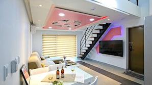 A modern living room with a staircase, a dining area, and a TV mounted on the wall. - Gyeongju The one Pension - Blue (Gyeongju)